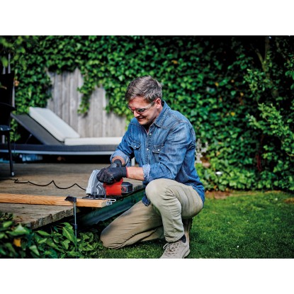 Férfi fát vág a piros Einhell TC-CS 1410 kézi körfűrésszel a kertben. Férfi fát vág a piros Einhell TC-CS 1410 kézi körfűrésszel a kertben.