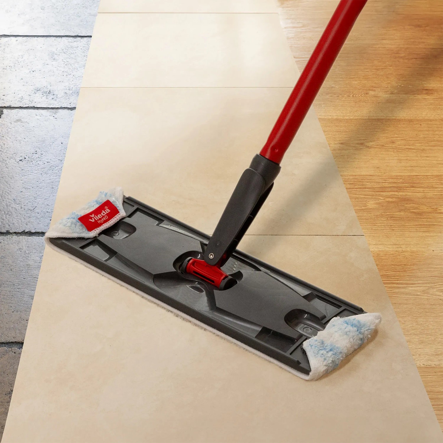 Vileda H2PrO lapos felmosó piros nyéllel és szürke felmosófejjel csempézett padlón. Vileda H2PrO lapos felmosó piros nyéllel és szürke felmosófejjel csempézett padlón.