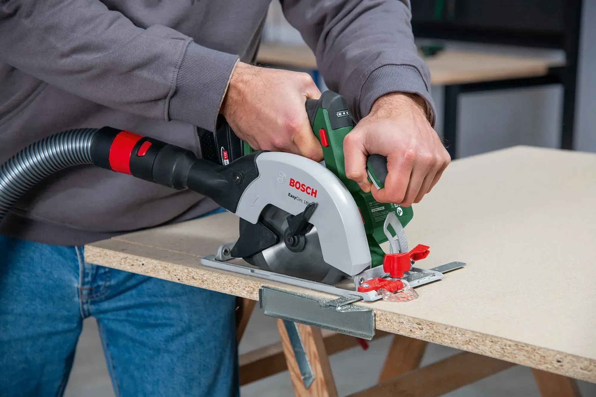 Bosch EasyCirc 18V-48 akkus kézi körfűrész használat közben porelszívással fafűrészelés közben. Bosch EasyCirc 18V-48 akkus kézi körfűrész használat közben porelszívással fafűrészelés közben.