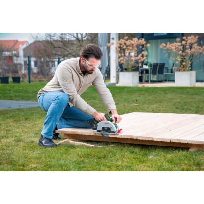 Férfi fát vág Bosch EasyCirc 18V-48 akkus kézi körfűrésszel. Körfűrész precíz favágásokhoz. Férfi fát vág Bosch EasyCirc 18V-48 akkus kézi körfűrésszel. Körfűrész precíz favágásokhoz.
