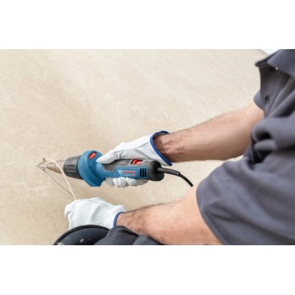 Bosch Professional GHG 20-60 hőlégfúvó használat közben, kék, fúvókával és kesztyűvel. Bosch Professional GHG 20-60 hőlégfúvó használat közben, kék, fúvókával és kesztyűvel.