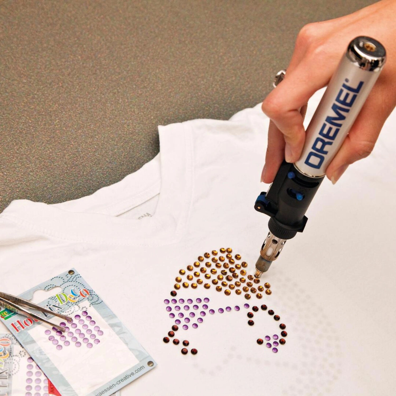 Dremel VersaTip forrasztópáka strasszköveket helyez fel egy pólóra. Dremel VersaTip forrasztópáka strasszköveket helyez fel egy pólóra.