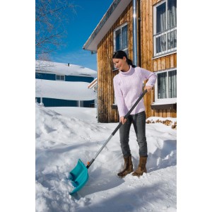 Nő használ Gardena combisystem alumínium nyelet 130 cm-es hótolólapáttal a hó eltakarításához egy ház előtt.