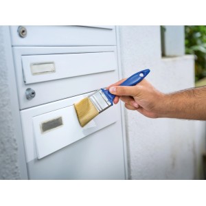 Kéz festi a postaládát LUX lapos ecsettel, lakk 30 mm. Kék nyelű ecset.