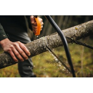 Fiskars SW31 fűrész, amint egy fatörzset vág. Kerti fűrész narancssárga fogantyúval.