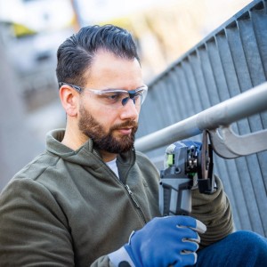 Férfi átlátszó LUX-TOOLS védőszemüveget visel fémmegmunkálás közben.