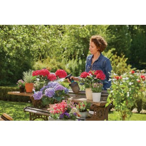 Nő virágokat locsol egy Gardena 1 literes pumpás permetezővel egy kerti padon.