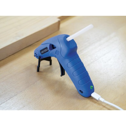 Kék LUX akkus hőolvadó ragasztópisztoly ragasztórúddal és USB töltőkábellel fa asztalon.