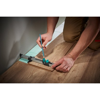 Wolfcraft illesztőkészlet laminált padlóhoz: A kézműves a laminált padlót illesztő eszközzel jelöli a falhoz.