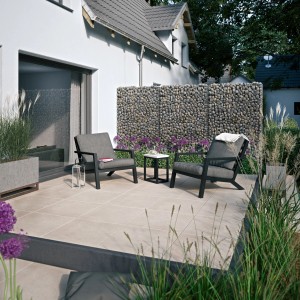 Terasz Tuscany Stone Beige porcelánlapokkal (60x60). Kerti bútorok és gabionfal a háttérben.