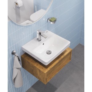 Grohe Dice S-Size króm egykaros mosdócsaptelep fehér mosdón, fa alsószekrényen, világoskék csempékkel.