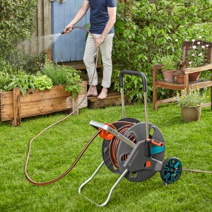 Gardena CleverRoll L Easy tömlőkocsi a kertben locsoló személlyel.