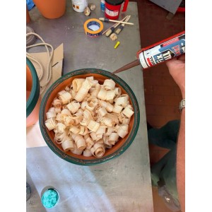 Kéz tart barna Soudal Fix All Flexi tömítőanyag kartust faforgács felett. Sokoldalú ragasztó szilikonhoz és akrilhoz.