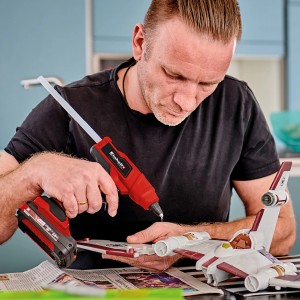 Férfi Einhell Power X-Change TE-CG 18 Li akkus ragasztópisztollyal barkácsol. Piros ragasztópisztoly akkumulátorral.