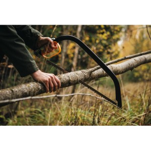 Fiskars SW30 fűrész használat közben: Egy személy ágat fűrészel a kertben.