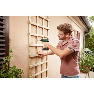 Bosch EasyDrill 18V-38 akkus csavarozó használat közben, fa rácsot csavaroz a ház falára.