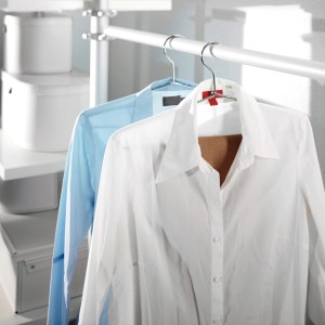 Két ing (kék, fehér) lóg vállfán egy textil szekrényben.