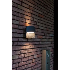 Modern Lutec Lotus antracit LED kültéri fali lámpa felfelé és lefelé irányuló fényhatással egy téglafalon.