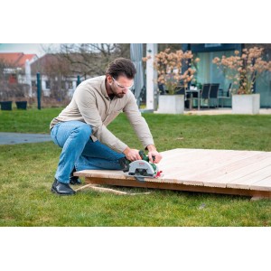 Férfi fát vág Bosch EasyCirc 18V-48 akkus kézi körfűrésszel. Körfűrész precíz favágásokhoz.