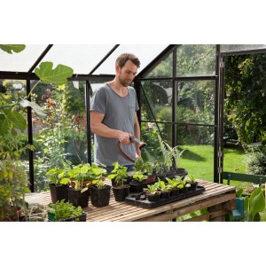 Férfi növényeket öntöz Gardena Comfort kerti locsolóval az üvegházban.