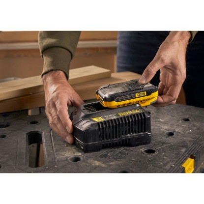 Stanley Fatmax V20 gyorstöltő akkumulátorral, akkumulátor töltése a munkaasztalon.