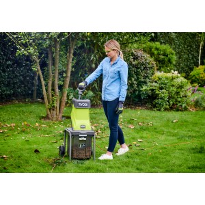 Nő Ryobi elektromos aprítógépet használ a kertben. Kertészkedés aprítógéppel.
