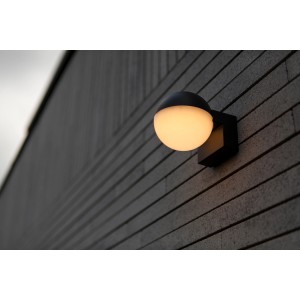 Modern LED kültéri fali lámpa t.b.t. kerek, világító gömbbel sötét homlokzaton.