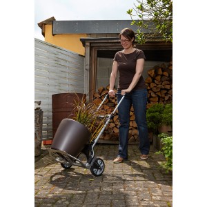 Nő szállít egy nagy cserepet a wolfcraft TS 850 összecsukható talicskával (100 kg teherbírás).