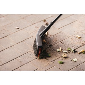 Fiskars Solid M univerzális seprű PowerClean sörtékkel, leveleket söpör térkövön.