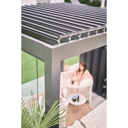 Biohort Pergola 5 x 3,5 m sötétszürke-ezüst színben, állítható lamellákkal és nővel a fotelben.