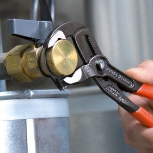Knipex Cobra vízpumpafogó 300 mm használat közben egy szelepen. A fogó szürke, atramentált és narancssárga fogantyúkkal rendelkezik.