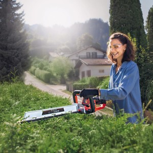 Nő sövényt vág az Einhell Power X-Change Arcurra 18/55 akkus sövényvágóval.