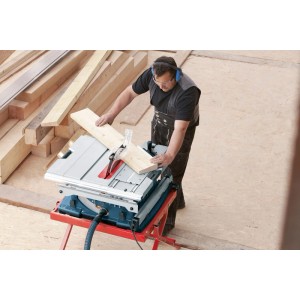 Férfi vág fát Bosch Professional GTS 10 XC asztali fűrésszel. Kék fűrész piros állvánnyal, Ø 254 mm fűrészlap.