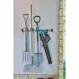 Gardena Gerätehalter Plus kerti szerszámokkal, például ásóval, gereblyével és lombfúvóval a falon.