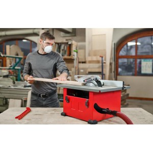 Einhell TC-TS 8 asztali körfűrész használat közben fával, porelszívással és védőfelszereléssel.