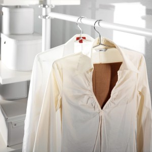 Ruhásszekrény fehér textil tárolódobozokkal és ingekkel a vállfákon.