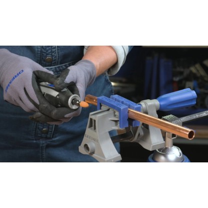 Dremel miniszerszám tartozékkal rézcsövet munkál meg tartóban. Dremel többcélú tartozékkészlet sokoldalú projektekhez.