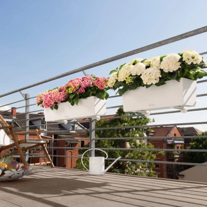 Két fehér Lechuza Balconera Color 80 virágláda rózsaszín és fehér hortenziákkal egy erkélyen.