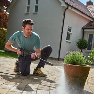 Férfi tisztít virágcserepet Bosch UniversalAquatak 125 magasnyomású mosóval.