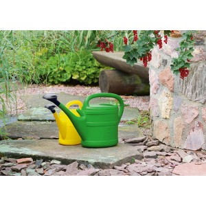 Zöld Geli locsolókanna (10 l) sárga locsolókanna mellett a kertben.