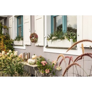 Fehér Lechuza Balconera Color 80 virágláda növényekkel egy ablak előtt.