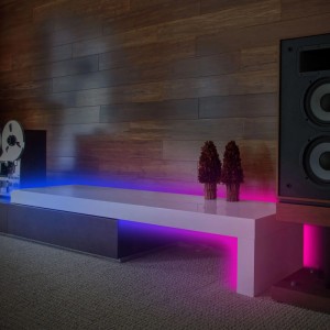 Brilo LED szalag Magic RGB színváltással és zenei érzékelővel, egy alacsony szekrényre szerelve.
