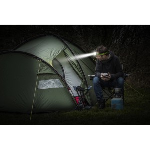 Férfi Energizer Vision HD+ fejlámpával a sátor előtt. LED zseblámpa erős fénnyel.